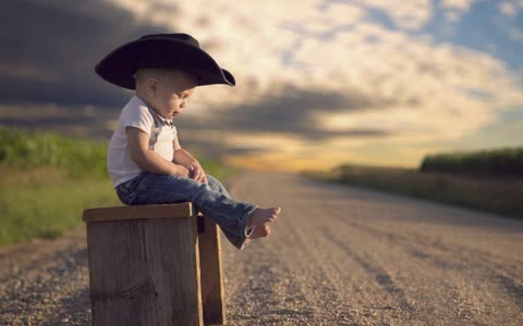 Маленький мальчик в шляпе у дороги