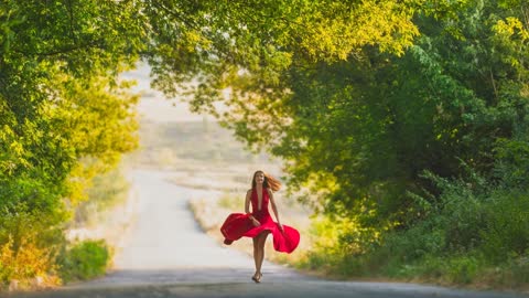 Девушка в красном платье идет по дороге