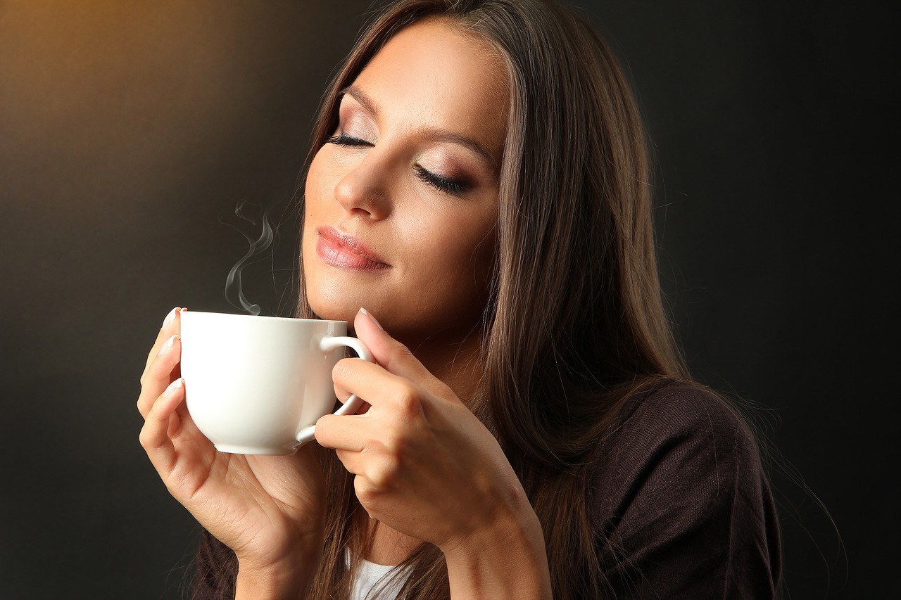 Девушка наслаждается ароматом кофе