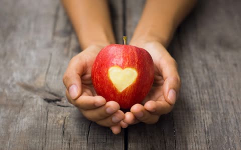 Яблоко в руках, вырезанное сердце
